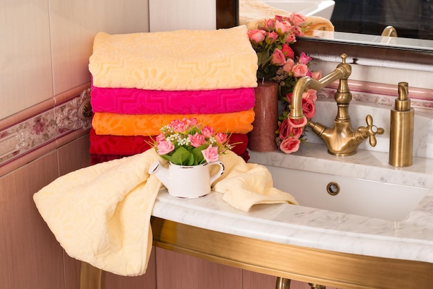 Eine Nahaufnahme von gefalteten bunten Bambushandtüchern auf einem Badezimmerschrank mit Blumenstraußdekoration