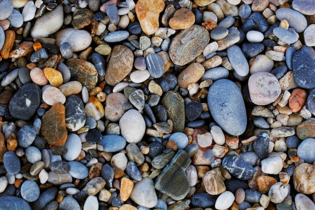Eine Nahaufnahme von glatten polierten mehrfarbigen Steinen, die am Strand an Land gespült wurden.