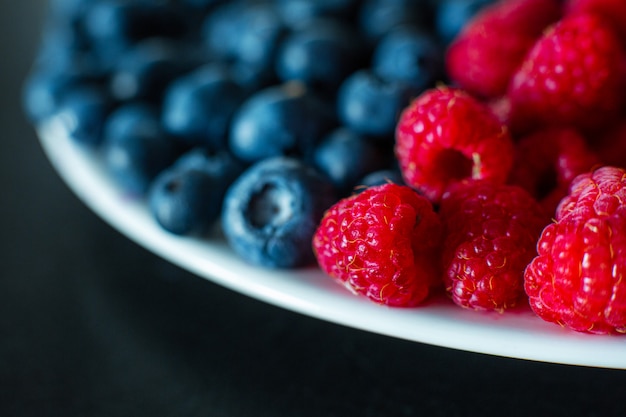 Eine Nahaufnahme von Himbeeren und schwarzen Blaubeeren teilte den Rahmen. Sommervitamine