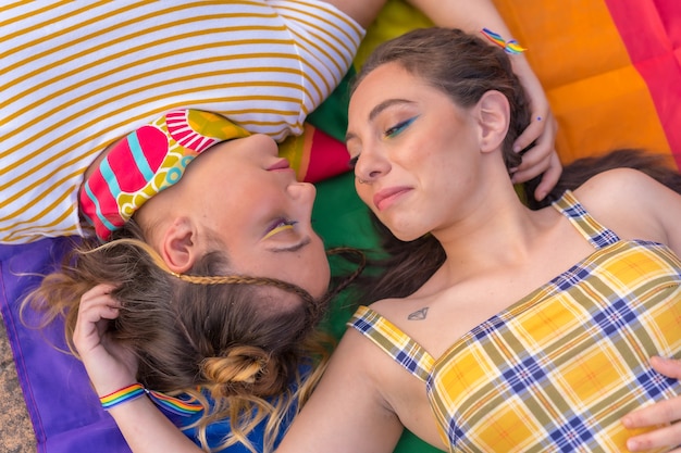 Eine Nahaufnahme von zwei jungen kaukasischen Frauen, die sich mit LGBT-Stolzflagge im Freien umarmen