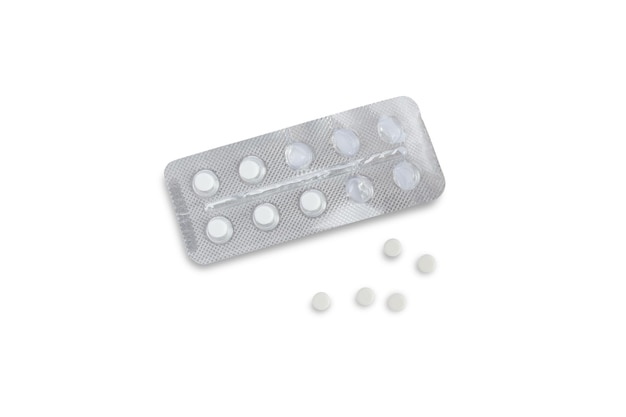 Eine offene Blisterpackung mit Tabletten und fünf Tabletten in der Nähe