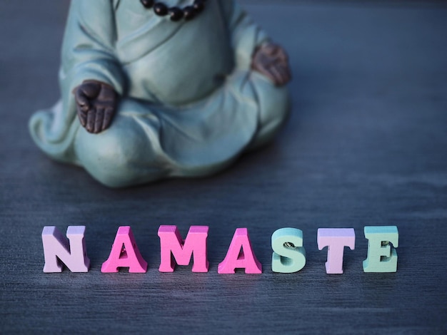 Eine Padmasana-Buddha-Statue befindet sich neben dem Wort NAMASTE Yoga-Konzept Namaste-Zeichen