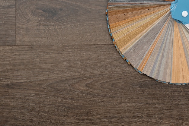 Eine Palette von Texturen und Dekorationen für den Holzboden aus Laminat und Vinyl auf einem dunklen Holztisch. Innenarchitektur. Haus planen und bauen.