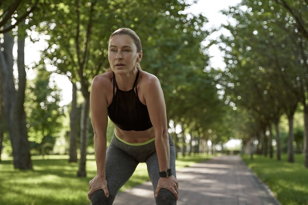 Eine Pause machen schöne Fitnessfrau in Sportkleidung, die nach dem morgendlichen Training müde wird