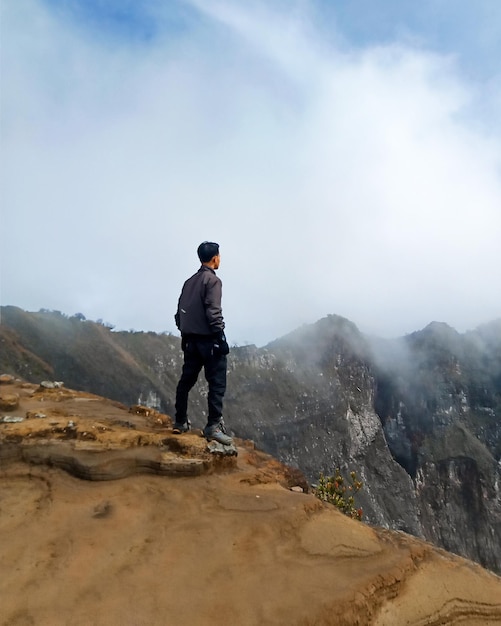 eine Person, die auf der Spitze eines Berges am Rand einer Klippe steht 2