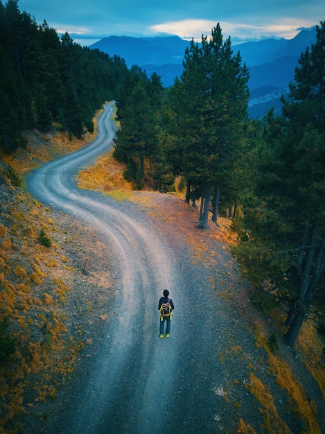 Eine Person, die auf einer unbefestigten Straße mit einem Berg im Hintergrund geht.