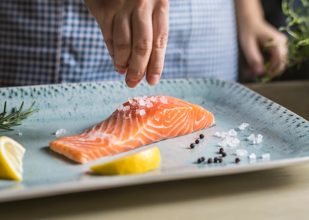 Eine Person, die ein Filet der Lachsnahrungsmittelphotographie-Rezeptidee würzt