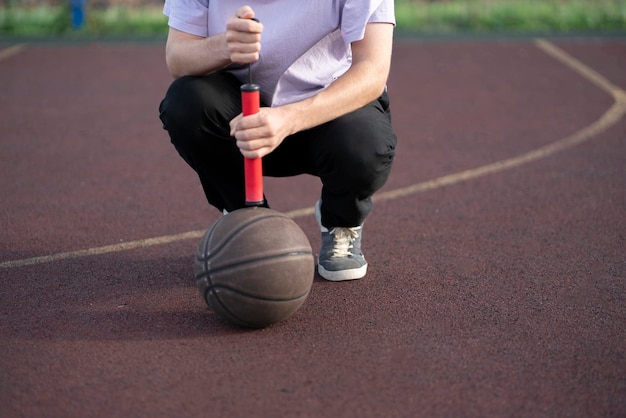 Eine Person, die eine rote Handpumpe und einen Basketballball hält