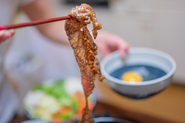 Eine Person, die einen Stock mit einer Schüssel mit Essen im Hintergrund hält