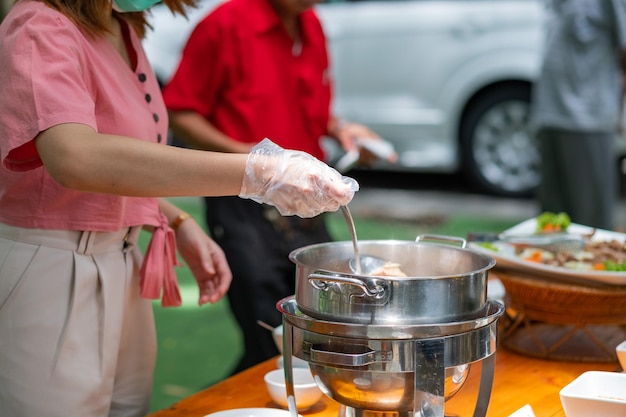 Eine person, die handschuhe trägt, die essen catering abendessen schaufeln, verhindern die coronavirus-krankheit covid 19