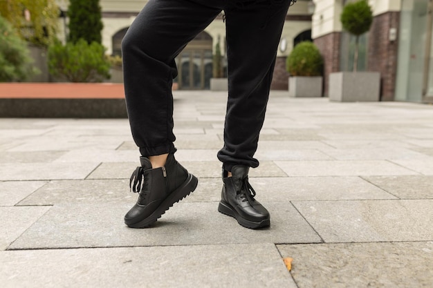 Eine Person, die schwarze Schuhe und ein Paar schwarze Lederstiefel trägt.