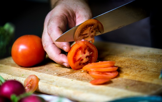 Eine Person, die Tomate schneidet