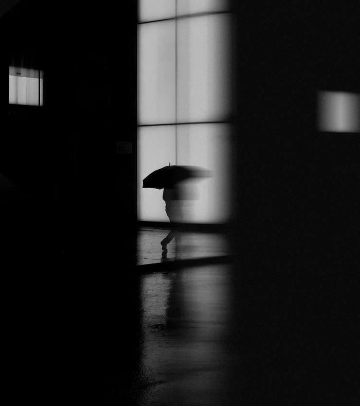 Foto eine person geht im dunkeln mit einem regenschirm