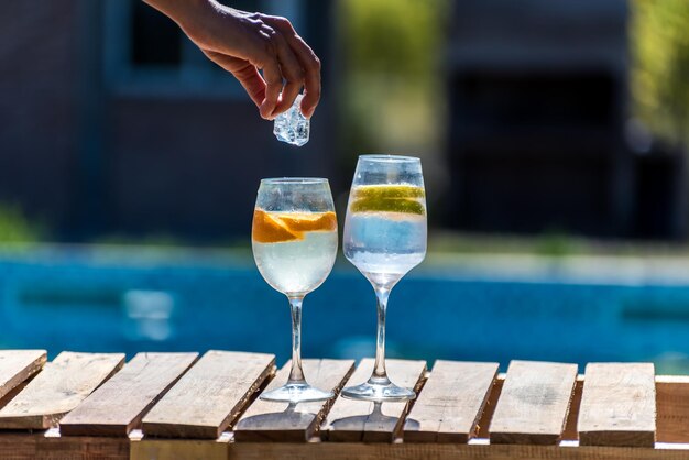 Eine Person gießt ein Glas Wasser in zwei Gläser.