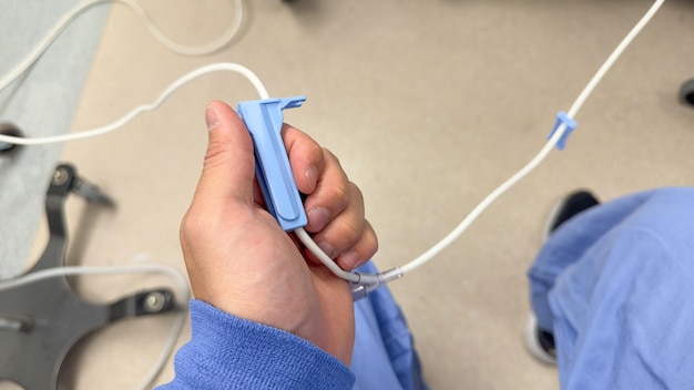 Foto eine person hält ein blaues plastikgerät, an dem ein weißes kabel befestigt ist.