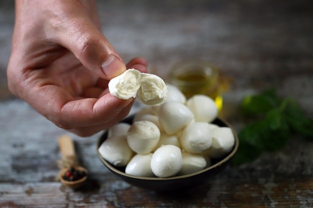 Eine Person hält ein Stück Mozzarella-Käse über eine Schüssel Mozzarella.