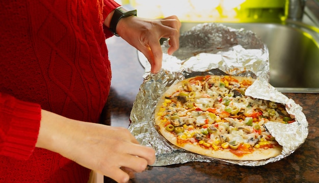 Eine Person hält eine Pizza in einer Zinnfolie