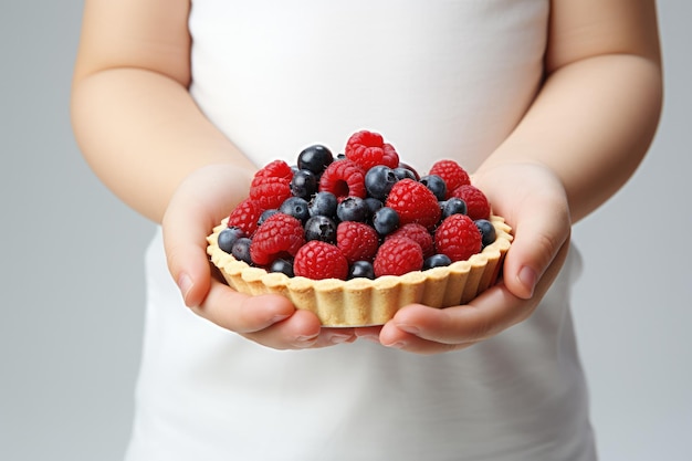 Eine Person hält einen Kuchen mit Beeren und Blaubeeren drin