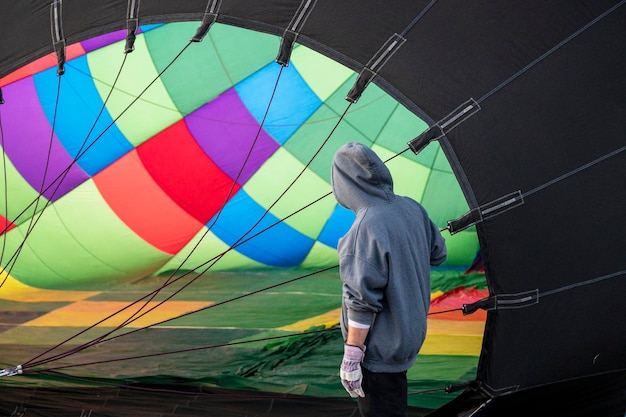 Eine Person in einem grauen Hoodie steht vor einem großen Heißluftballon.