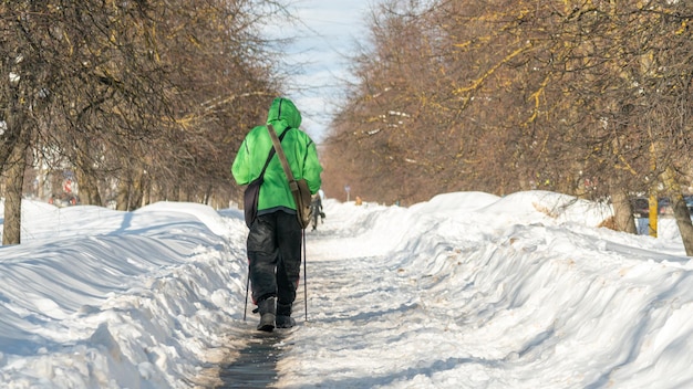 Eine Person in einer grünen Jacke fährt auf einem verschneiten Weg Ski.