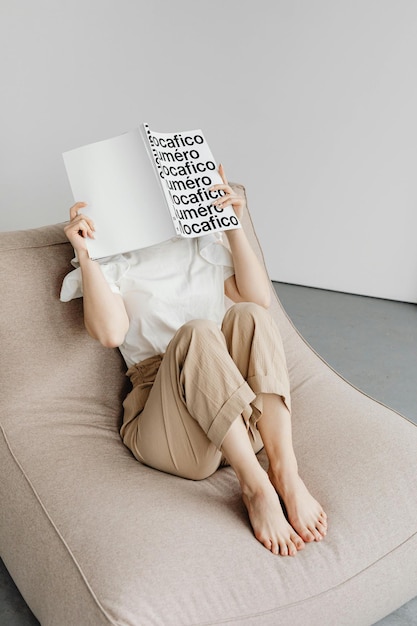 Eine Person liest ein Buch, während sie auf einem bequemen Stuhl sitzt Foto