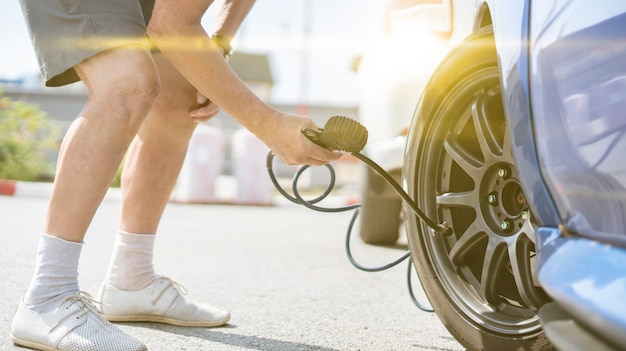 Eine Person pumpt die Reifen der Autoräder mit einem Kompressor mit Manometer auf