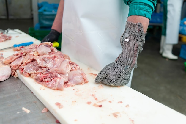 Eine Person schneidet mit einem Handschuh ein Stück Fleisch.