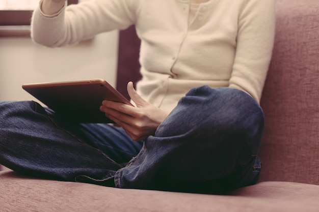 Eine Person sitzt auf einer Couch mit einem Tablet auf dem Schoß und dem Wort Kaffee auf dem Bildschirm.