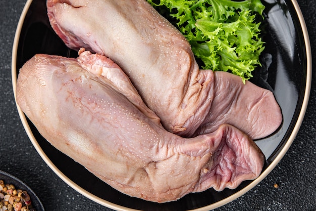 Eine Pfanne mit rohen Hähnchenschenkeln und einem Bund Salat darauf