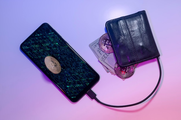 Eine physische Bitcoin-Münze auf einem Handy, das über ein Kabel mit einer Brieftasche verbunden ist, aus der Dollarscheine und Bitcoin-Münzen herausragen Konzept der digitalen Brieftasche