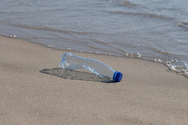 Eine Plastikflasche liegt am Strand und verschmutzt das Meer