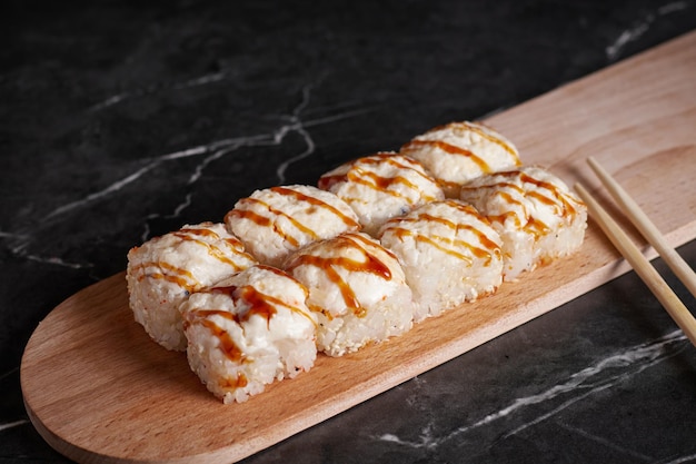 Eine Portion Brötchen auf einem Ständer, japanisches Essen, Sushi auf dem Tisch, chinesische Essstäbchen, dunkler Hintergrund