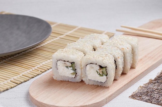 Eine Portion Brötchen auf einem Ständer, japanisches Essen, Sushi auf dem Tisch, chinesische Essstäbchen, heller Hintergrund