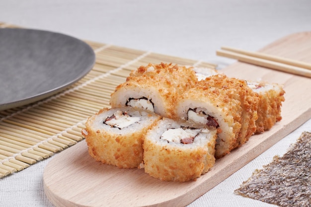 Eine Portion Brötchen auf einem Ständer, japanisches Essen, Sushi auf dem Tisch, chinesische Essstäbchen, heller Hintergrund