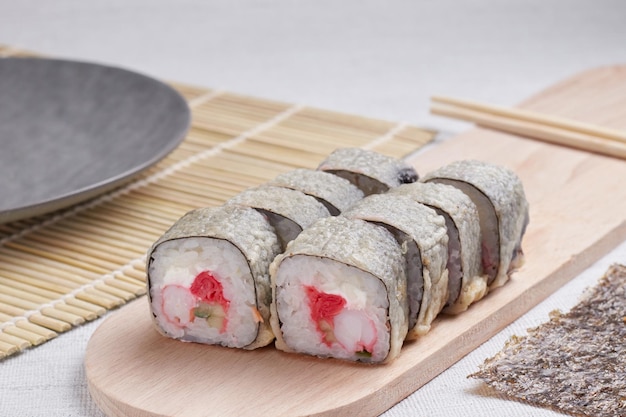 Eine Portion Brötchen auf einem Ständer, japanisches Essen, Sushi auf dem Tisch, chinesische Essstäbchen, heller Hintergrund