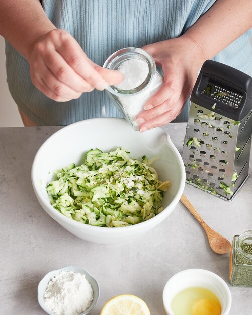 Foto eine prise salz in der hand einer frau rezeptzubereitung mit geriebener zucchini