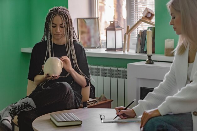 Eine Psychologin arbeitet in ihrem Büro mit einer jungen Klientin mit Dreadlocks auf dem Kopf