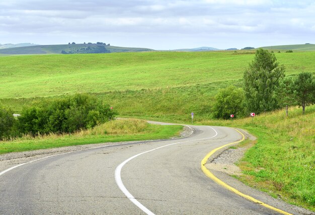 Eine Regionalstraße in einer ländlichen Gegend in der Steppe vor dem Hintergrund grüner Hügel