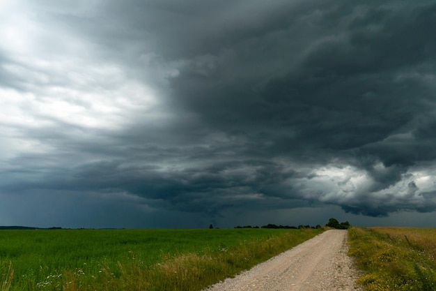 Eine regnerische graue Wolke schwebte über dem Feld Ein Hurrikan über einem landwirtschaftlichen Feld Dirt Landstraße dramatische Szene