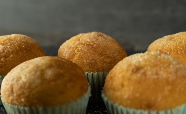 Eine Reihe köstlicher frisch gebackener Cupcakes mit Zucker oben auf einem Hintergrund
