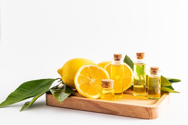 Eine Reihe verschiedener Flaschen mit einem Stopfen mit ätherischem Zitronenöl oder natürlichem Öl auf einem Holzbrett zwischen reifer Frucht-Aromatherapie-Entspannung