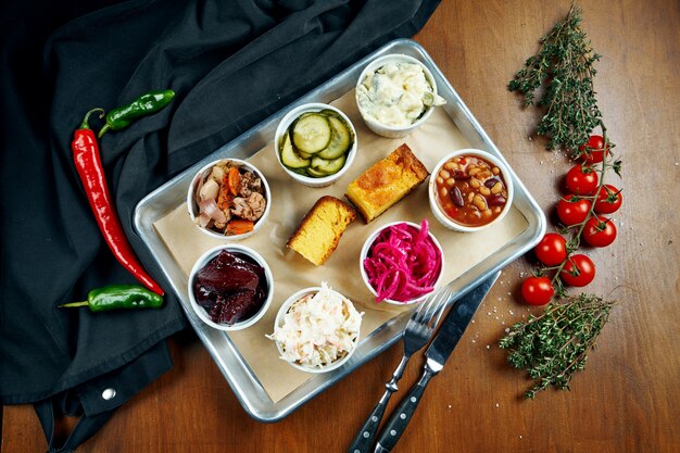 Eine reihe verschiedener snacks für fleisch - eingelegte gurken, cole slow salat, chili con carne, gekochte rote beete