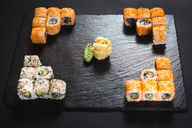 Eine Reihe verschiedener Sushi-Rollen mit Kaviar auf schwarzem Hintergrund