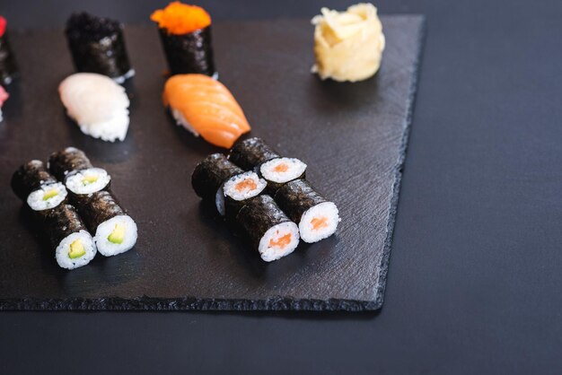 Eine Reihe verschiedener Sushi-Rollen mit Kaviar auf schwarzem Hintergrund