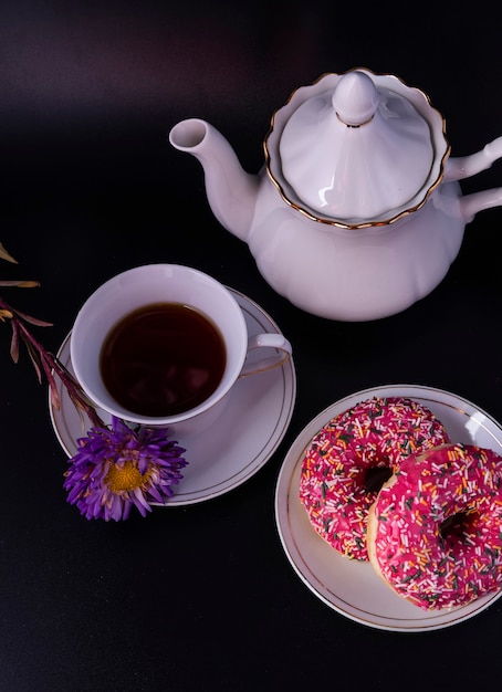 Eine Reihe von Donuts für die Teezeremonie mit Zuckerguss und einer Blume auf schwarzem Hintergrund.