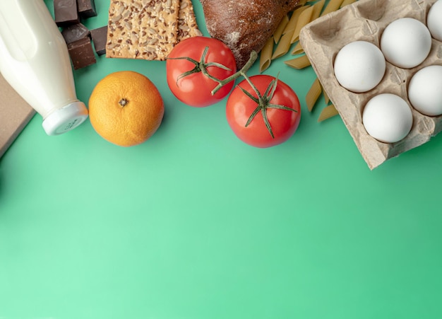 Eine Reihe von frischen Produkten für eine gesunde Ernährung auf grünem Hintergrund. Sortiment für die Essenslieferung. Draufsicht und Kopierbereich