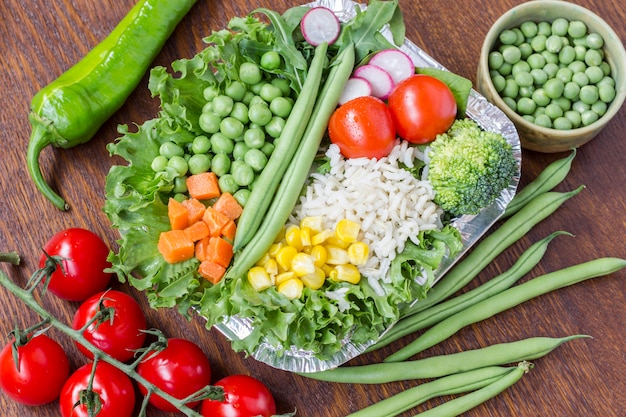 Eine Reihe von Gemüse mit Reis für eine gesunde Ernährung: Mais, Erbsen, Spargel, Karotten, Brokkoli, Salat