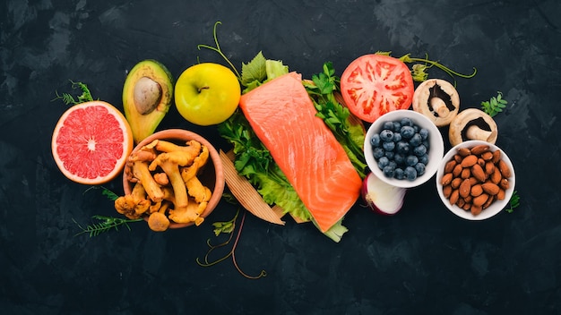 Eine Reihe von gesunden Lebensmitteln auf einem Steintisch Fisch Gemüse Obst Nüsse Beeren Pilze Draufsicht Freier Platz für Text