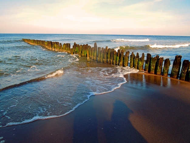 Eine Reihe von Holzpfosten im Meer gegen den Himmel beim Sonnenuntergang
