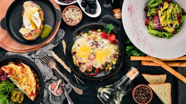 Eine Reihe von Lebensmitteln Shakshuka-Omelett-Avocado-Salat-Sandwich mit pochiertem Ei Auf einem hölzernen Hintergrund Freier Platz für Text Ansicht von oben